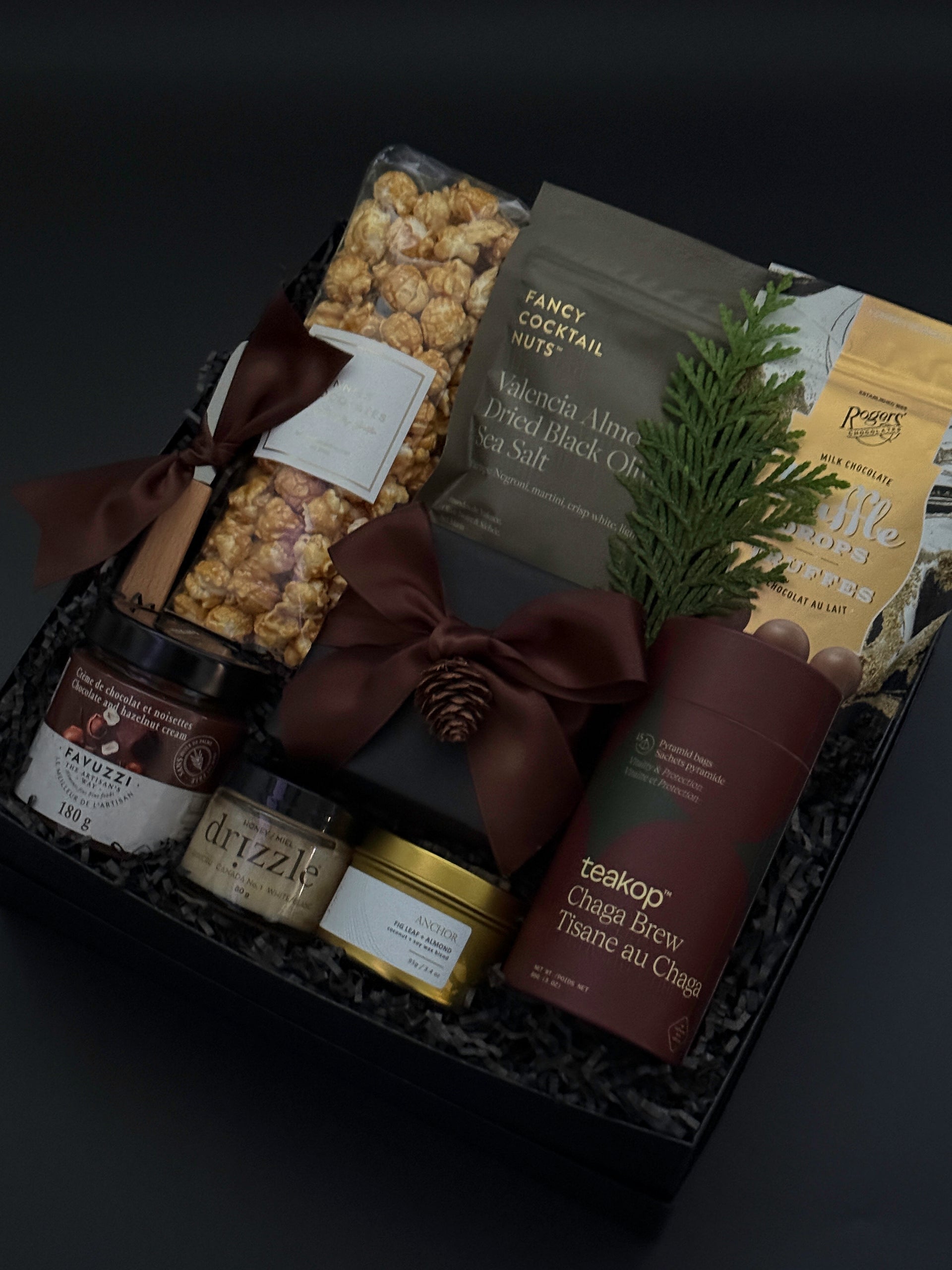 Gourmet gift basket with snacks, coffee, and a bottle on a dark background