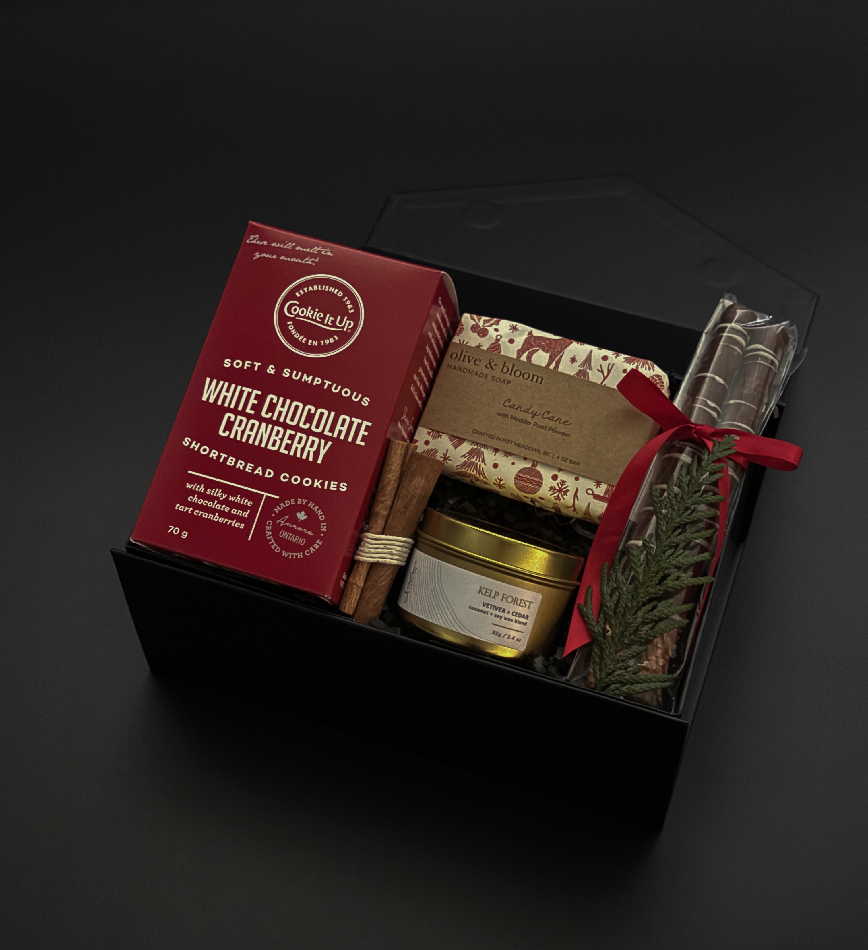 Gourmet gift set with cookies, tea, and other items on a dark background
