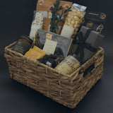 Gourmet chocolate assortment, artisanal raw honey, and forest fir candle styled in a refined metropolitan gift basket