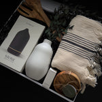 Close up of luxury housewarming gift box with Vitruvi diffuser Turkish towel and olive wood snack bowl by Muse Baskets and Co