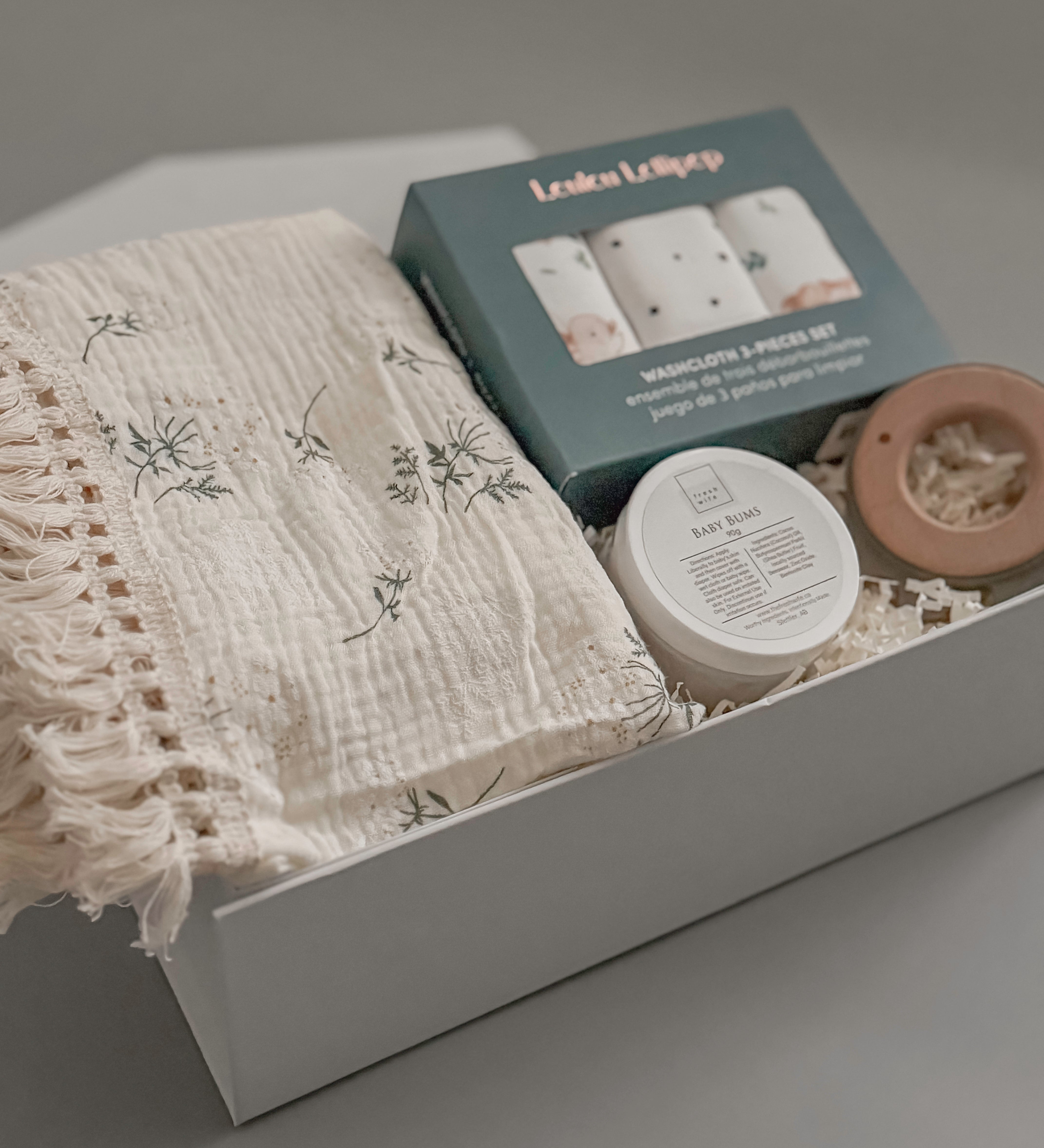 Close up of Loulou Lollipop washcloth set fringe blanket and Baby Bums cream in a white gift box