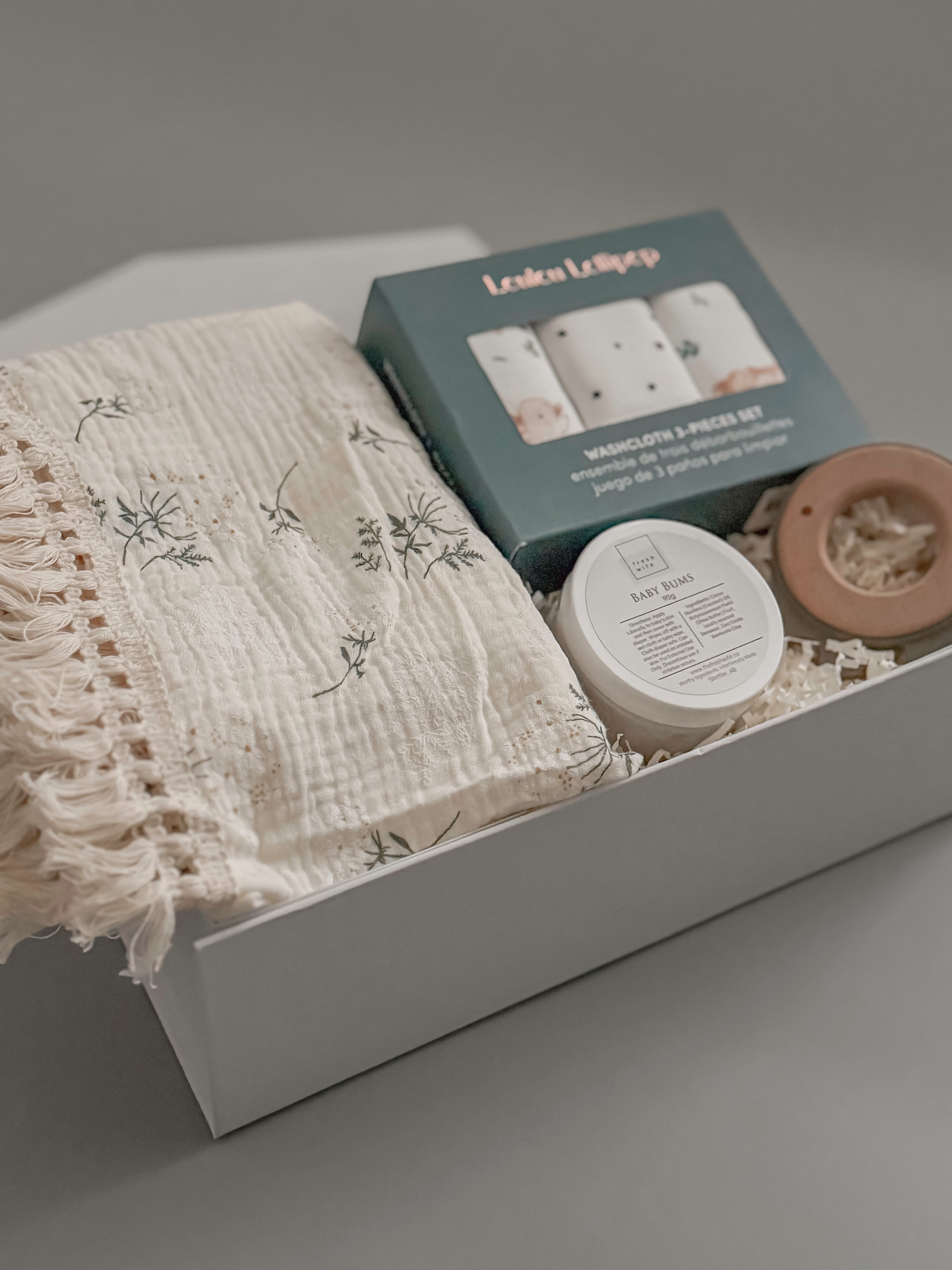Close up of Loulou Lollipop washcloth set fringe blanket and Baby Bums cream in a white gift box