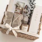 The Estate client appreciation gift with architectural bookends, Magnolia Table and Poet Farm Co. home fragrance arranged in a wicker basket.