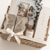The Estate client appreciation gift with architectural bookends, Magnolia Table and Poet Farm Co. home fragrance arranged in a wicker basket.