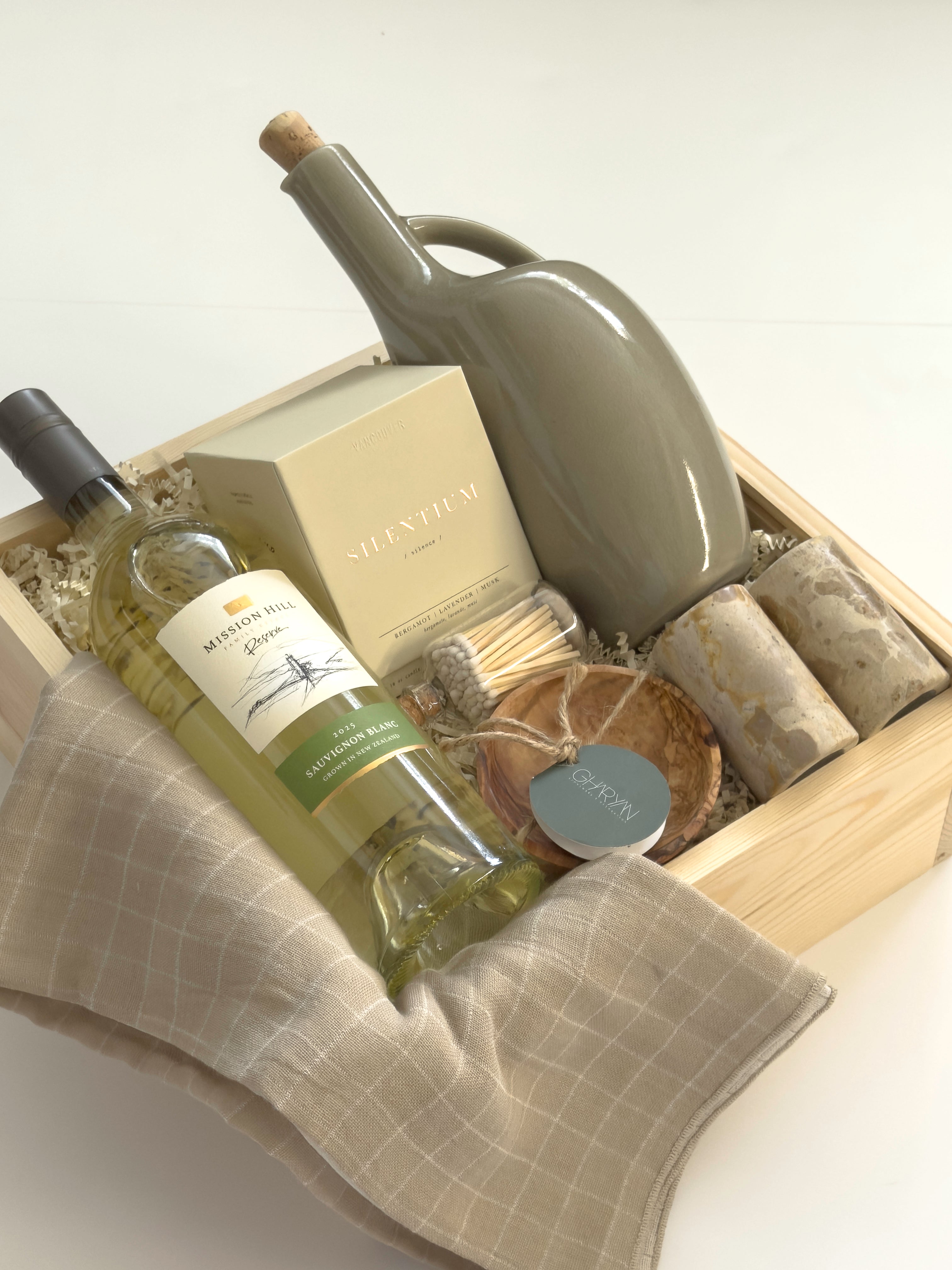 Vancouver Thanksgiving gift basket by Muse Baskets and Co. with Mission Hill wine, Vancouver Candle Co. candle, Matchstick Boutique matches, Gharyan Stoneware pieces and Danica Brands dishtowels in a wood gift box.
