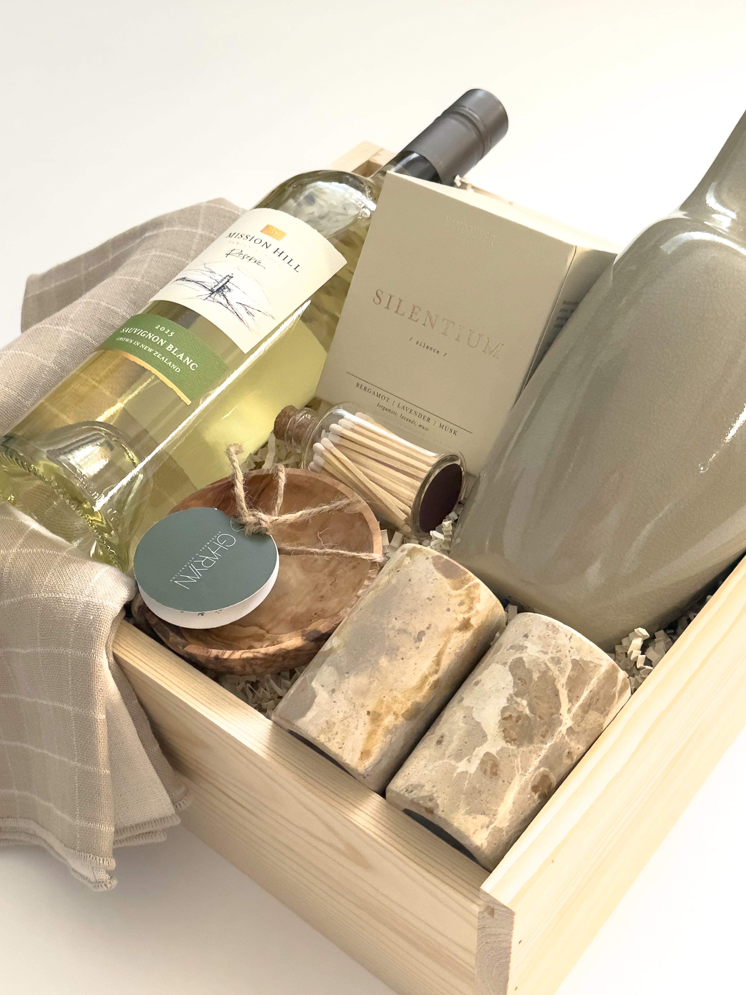 Realtor and client appreciation gift basket by Muse Baskets and Co. featuring wine, candle, stoneware, marble salt and pepper shakers, olive wood and soft grey dishtowels for a refined home gifting experience.