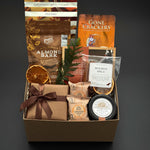 Cedar & Clove holiday gift box by Muse Baskets and Co. with maple pecans, brie, salmon and chocolate in a kraft box finished with brown satin ribbon.