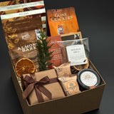 Cedar & Clove holiday gift box by Muse Baskets and Co. with Fig & Walnut Wine Preserve, savoury crackers and brie wrapped in brown paper and ribbon.