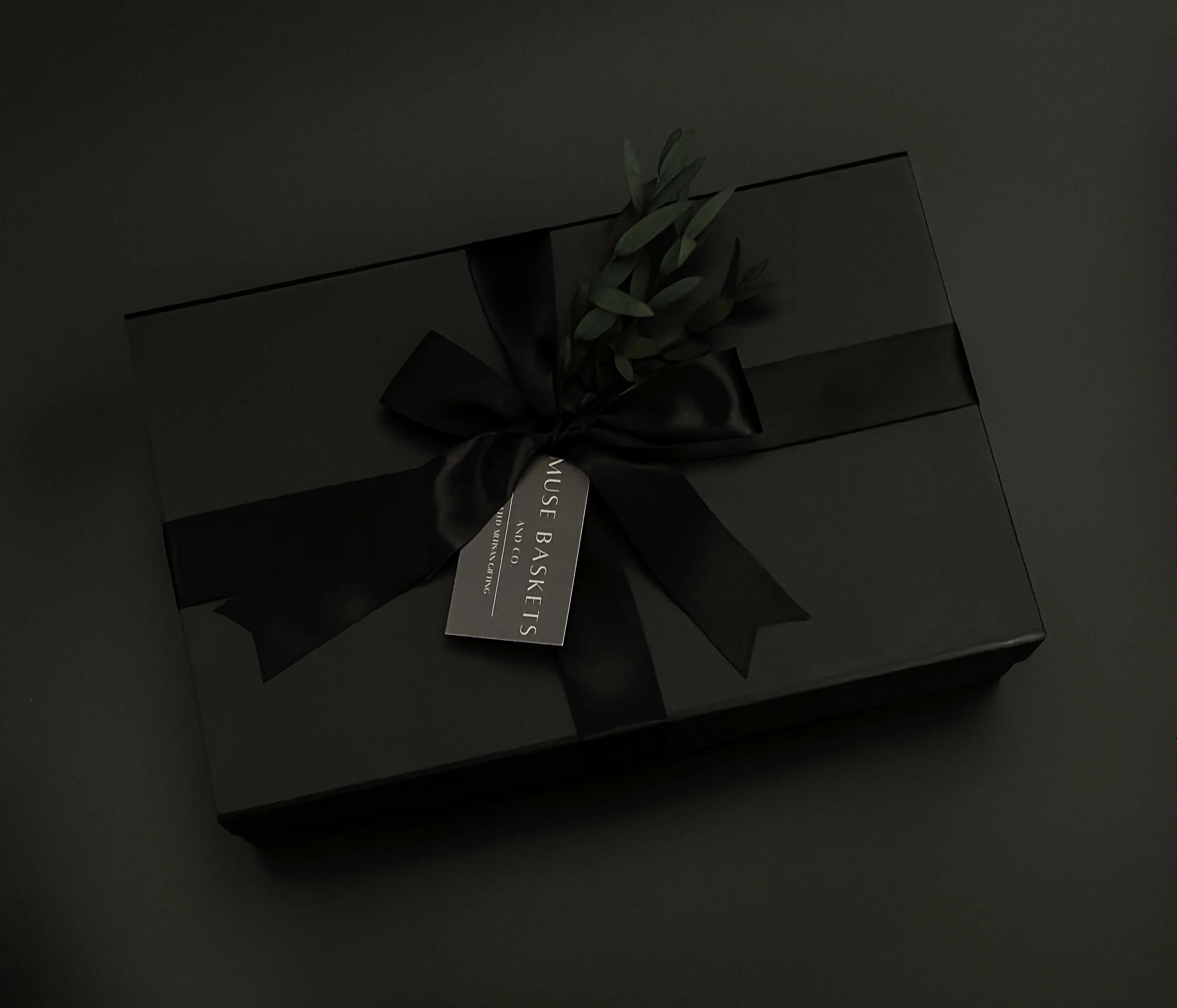 closed gift box with a ribbon, gift tag and sprig of greenery