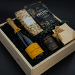 Gift basket with champagne, pretzels, and other snacks on a dark background