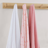 Three swaddles in white, pink, and red hanging on a wooden rod against a light background.