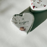 Close-up of a Reverie heart-shaped bath bomb with dried floral accents, a self-care product featured in Muse Baskets and Co. gift baskets