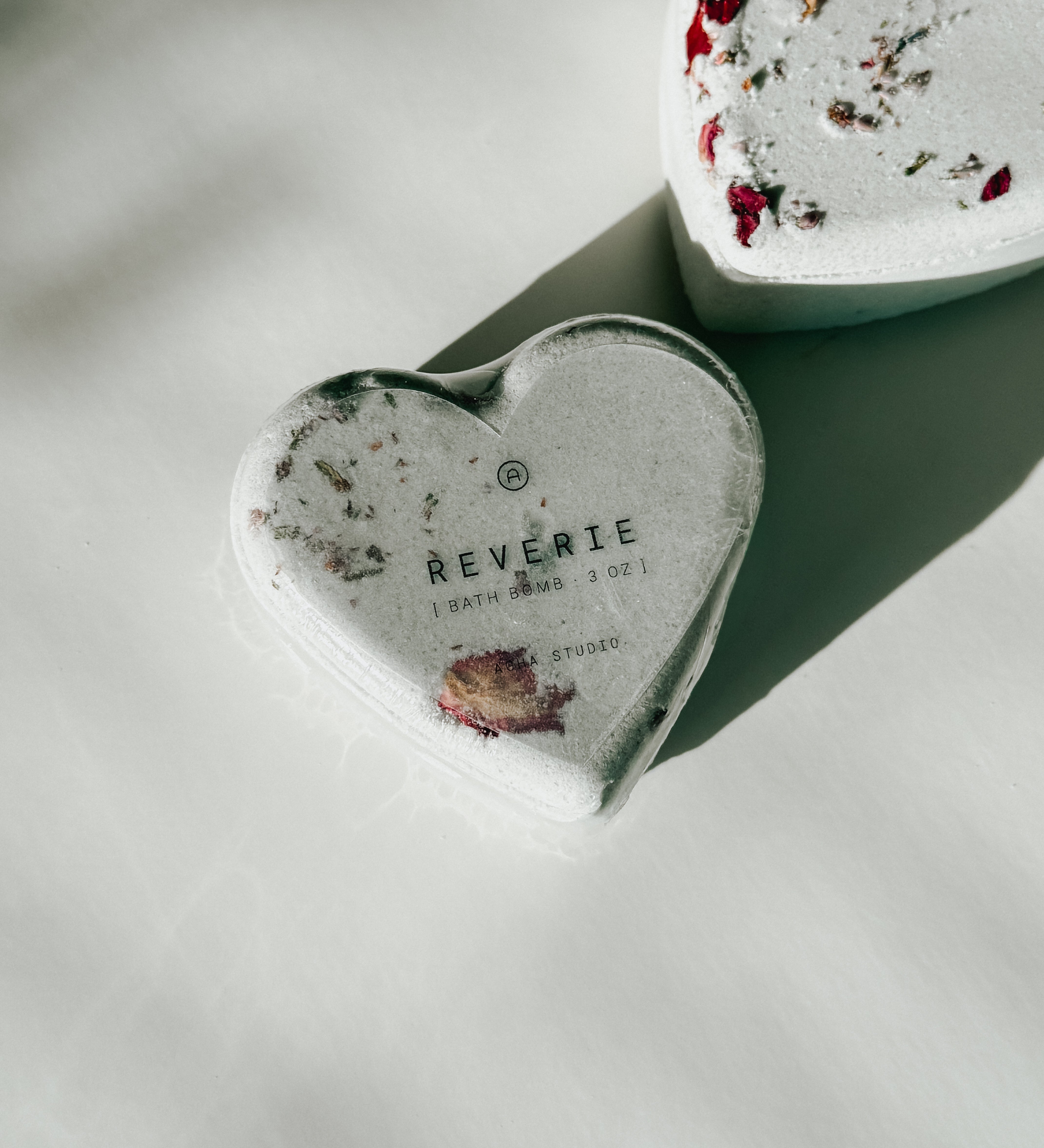 Close-up of a Reverie heart-shaped bath bomb with dried floral accents, a self-care product featured in Muse Baskets and Co. gift baskets
