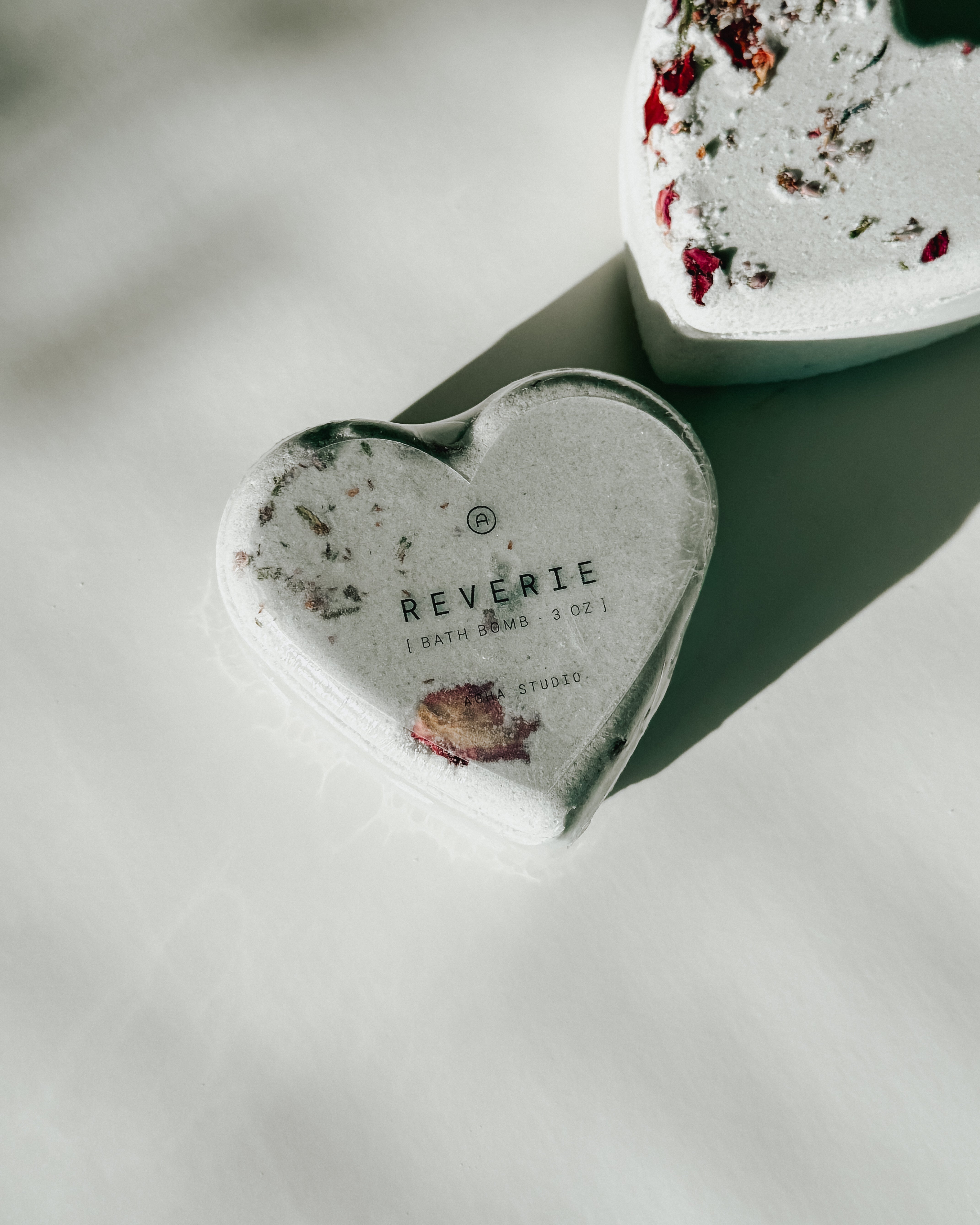 Close-up of a Reverie heart-shaped bath bomb with dried floral accents, a self-care product featured in Muse Baskets and Co. gift baskets