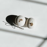 Two round bath bombs decorated with dried flowers and tied with twine, a self-care product featured in Muse Baskets and Co. gift baskets