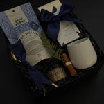 Sanctuary in Winter gift box featuring winter wellness tea, milk chocolate bar, honey, stoneware mug, and seasonal accents in a black bo