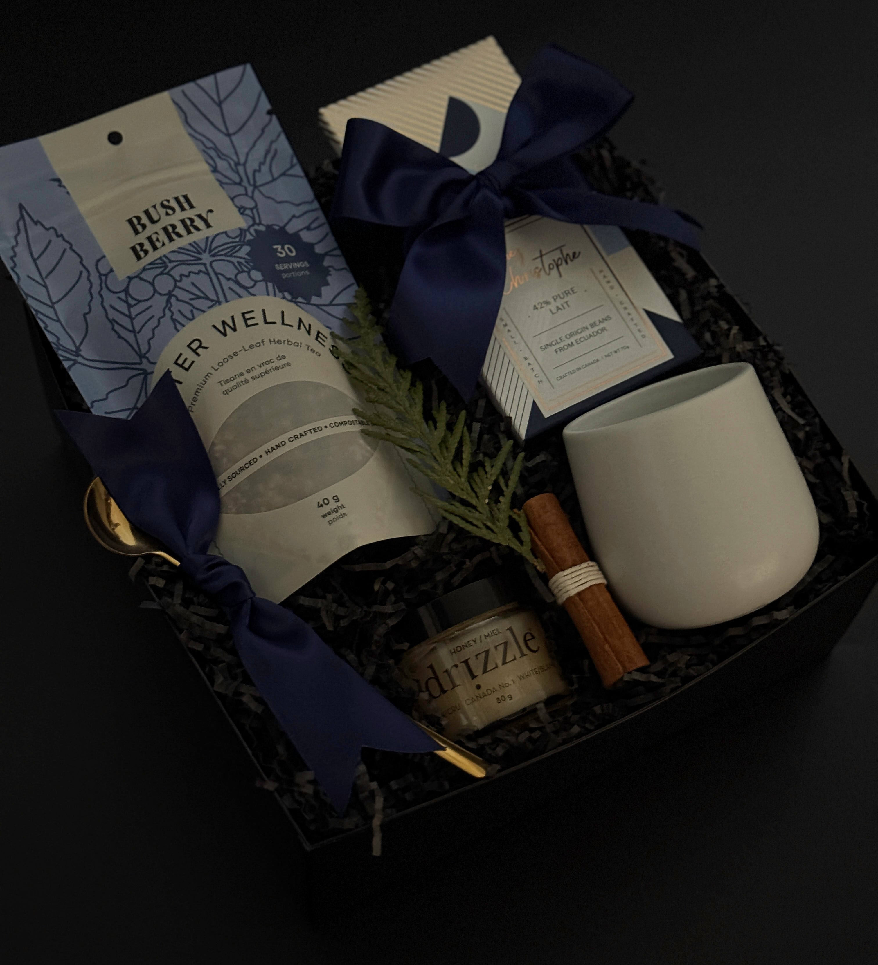 Sanctuary in Winter gift box featuring winter wellness tea, milk chocolate bar, honey, stoneware mug, and seasonal accents in a black bo