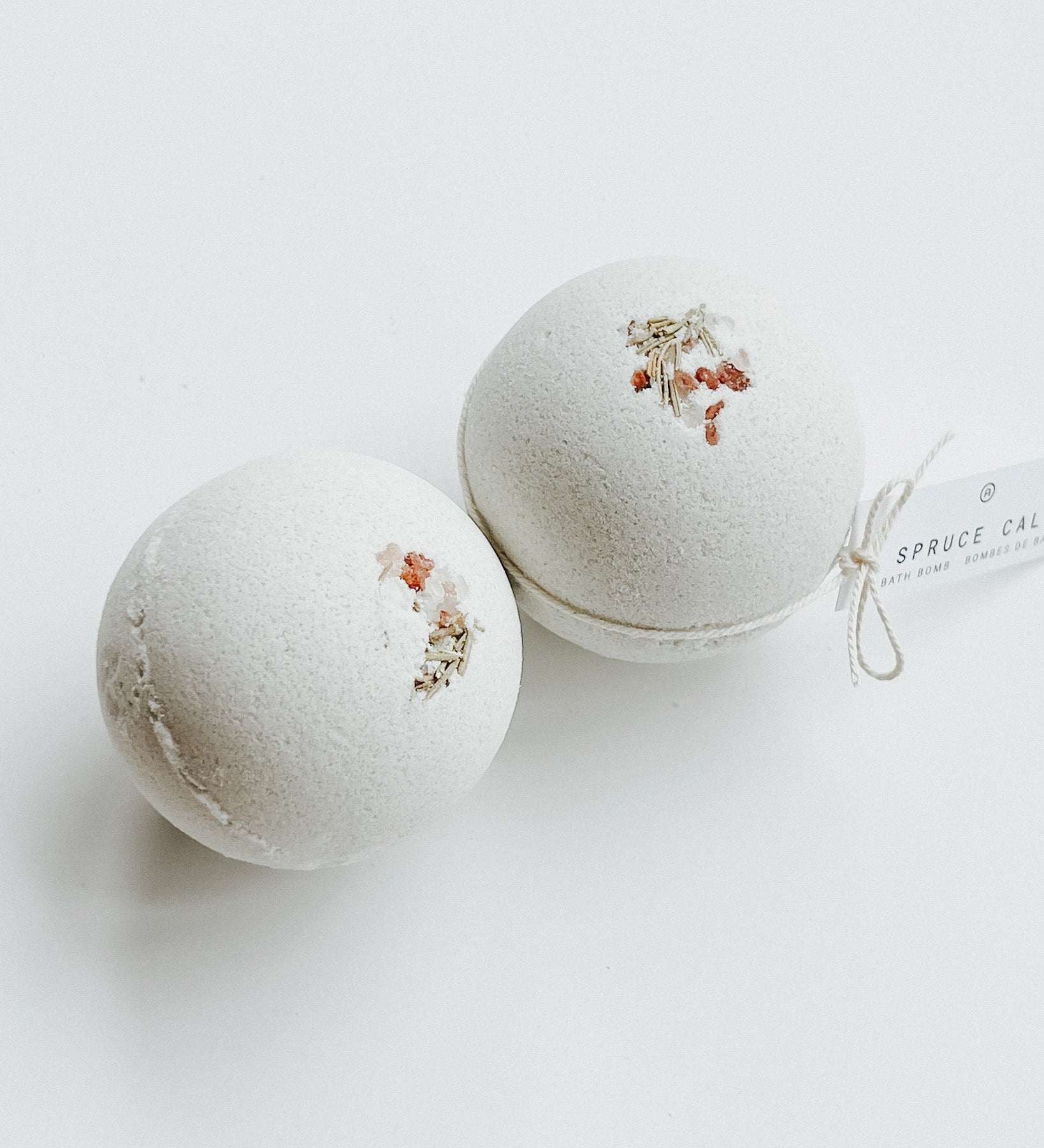 Two Spruce Calm bath bombs decorated with dried flowers, a self-care product featured in Muse Baskets and Co. gift baskets