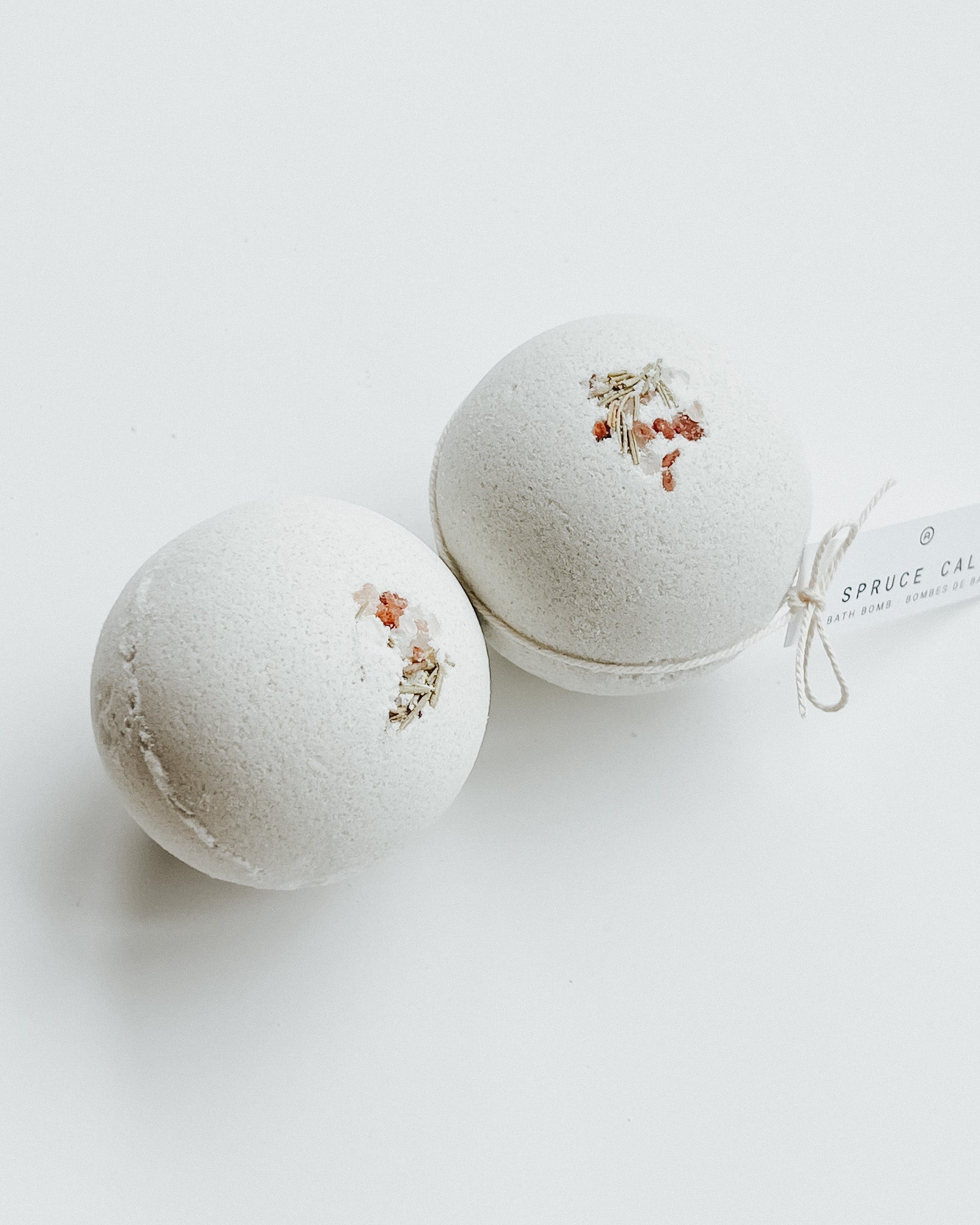 Two Spruce Calm bath bombs decorated with dried flowers, a self-care product featured in Muse Baskets and Co. gift baskets