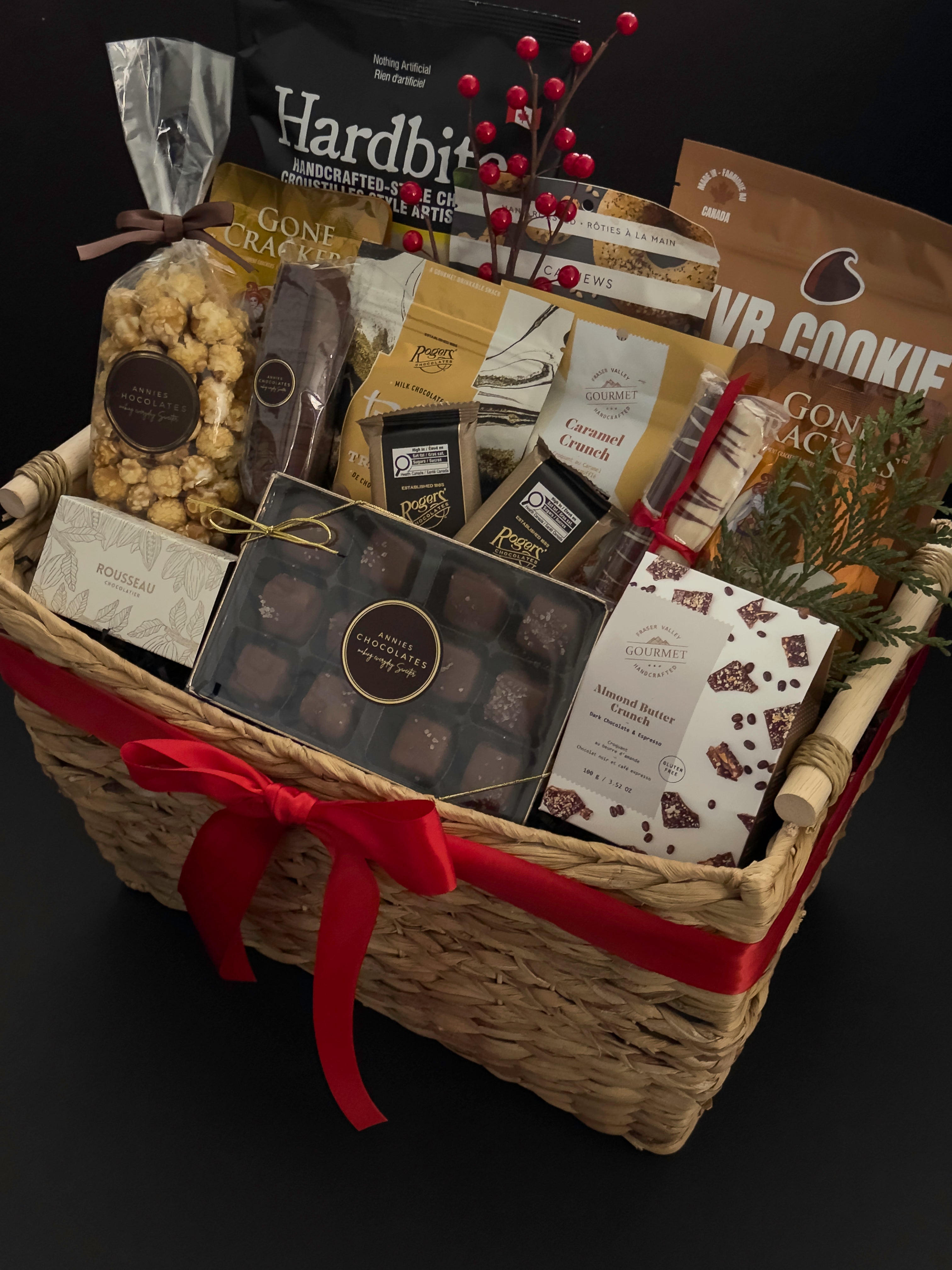 Corporate holiday gift basket by Muse Baskets and Co. featuring Canadian artisan treats, chocolates, popcorn, crackers and a polished woven basket presentation.