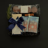 The Chocolate Indulgence gift box with artisan chocolate bar, hot chocolate mixes, sandwich cookies, and holiday accents in a black gift box.