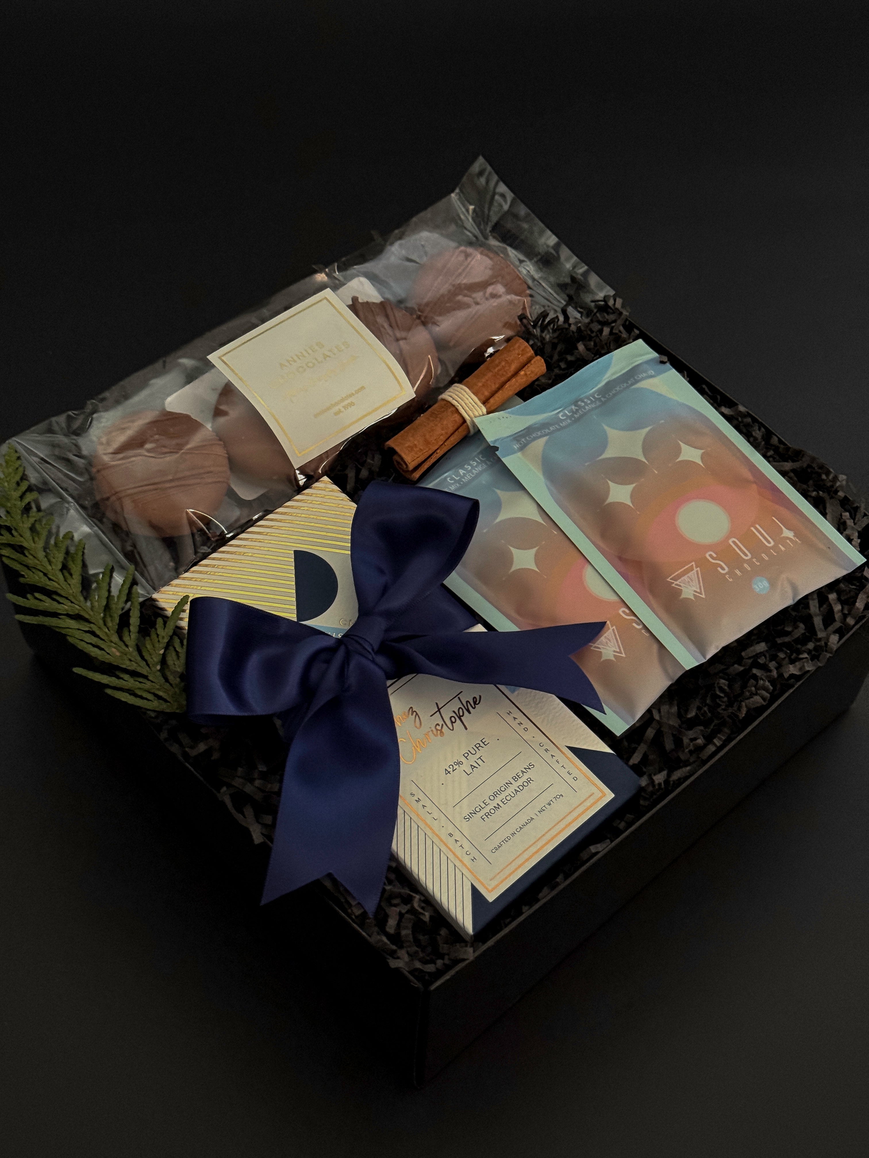Flat lay of The Chocolate Indulgence gift box with cocoa, chocolate bar, cookies, and festive cinnamon bundle.