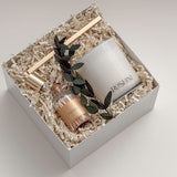 Lumière gift box by Muse Baskets and Co. photographed at an angle, with a white Roshni candle, gold candle snuffer, white tipped home matches, and preserved eucalyptus nestled in a white gift box, a calming sympathy gift, client care gift, and homeowner welcome gift from Canadian makers.