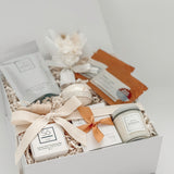 Gift box with skincare products including a candle, soap, and lotion on a white background