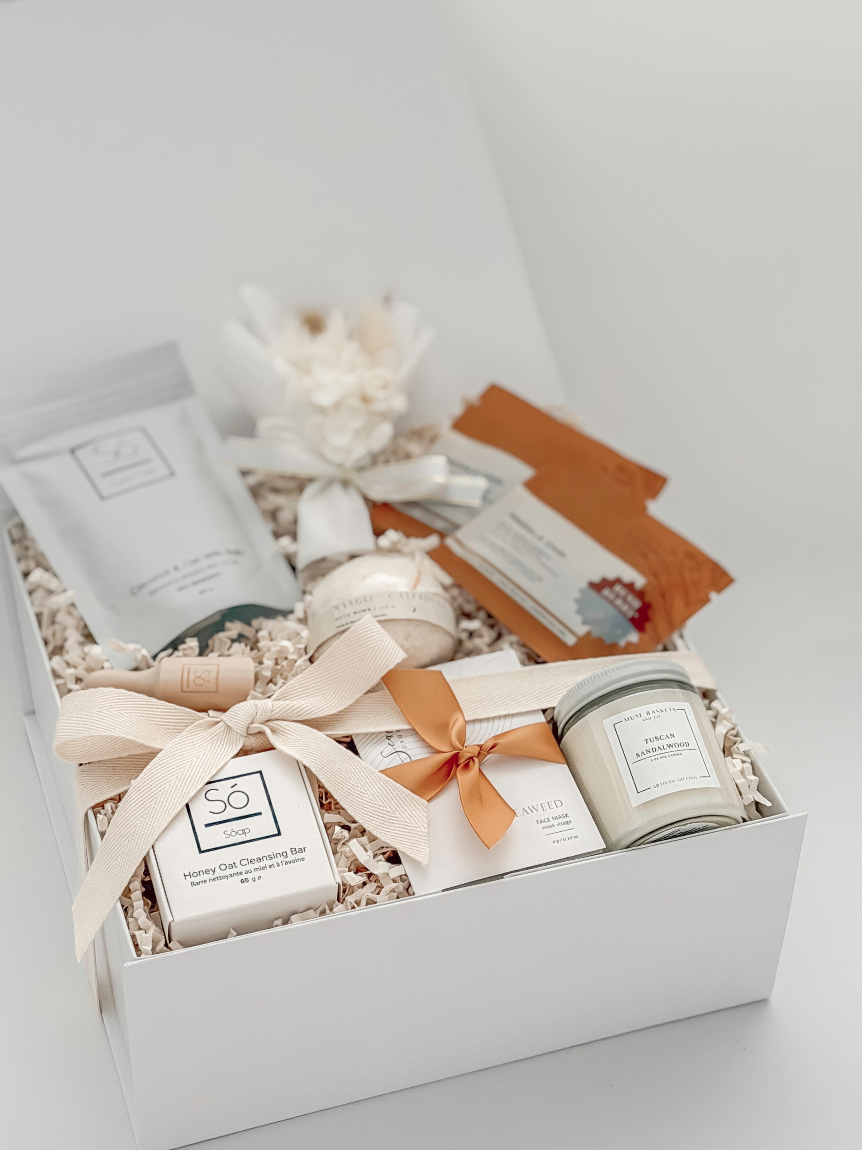 Gift box with skincare products including a candle, soap, and lotion on a white background