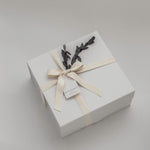 White gift box with a bow and decorative elements on a light gray background