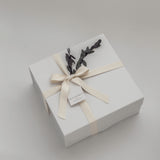 White gift box with a bow and decorative elements on a light gray background