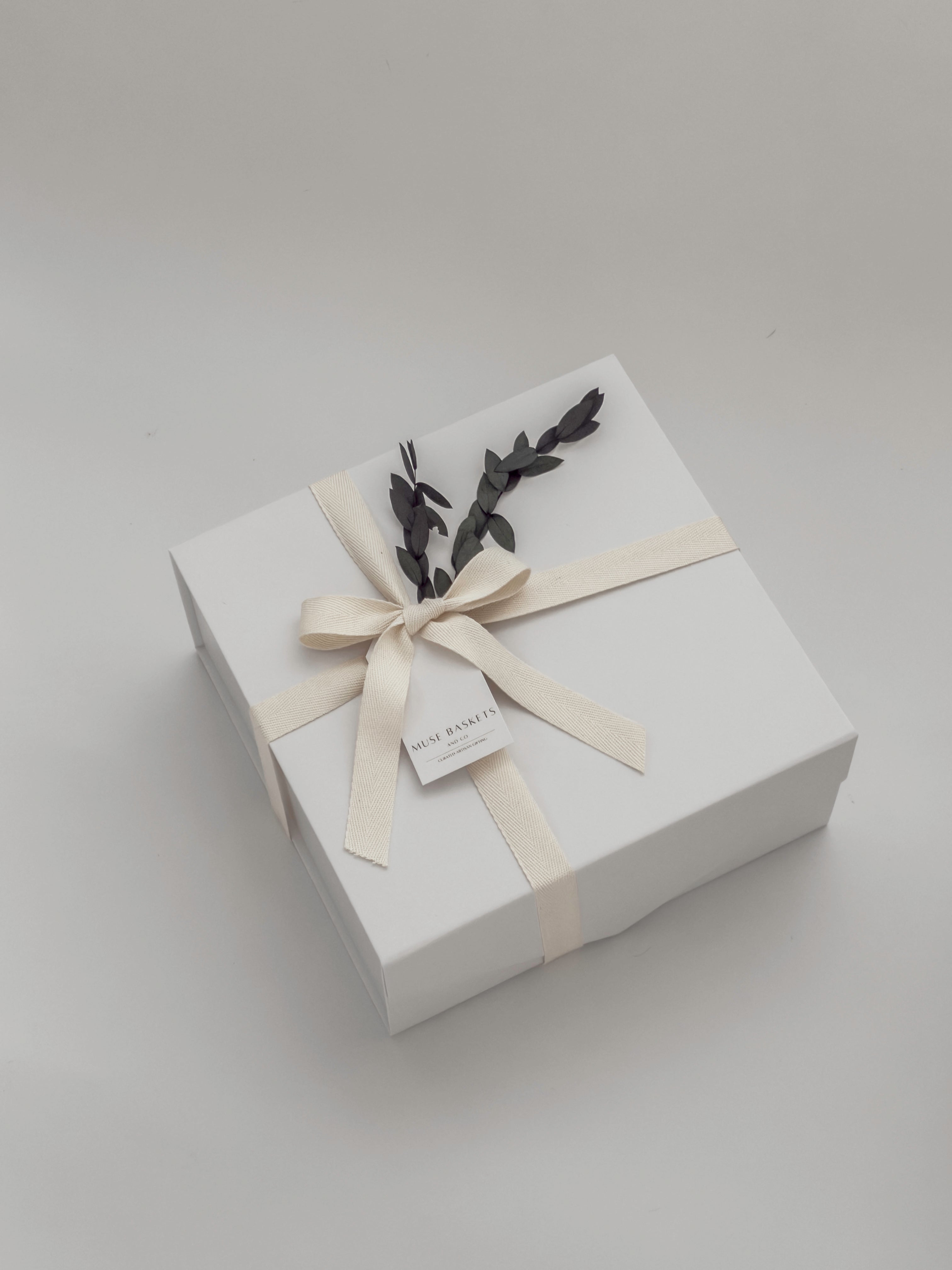 White gift box with a bow and decorative elements on a light gray background