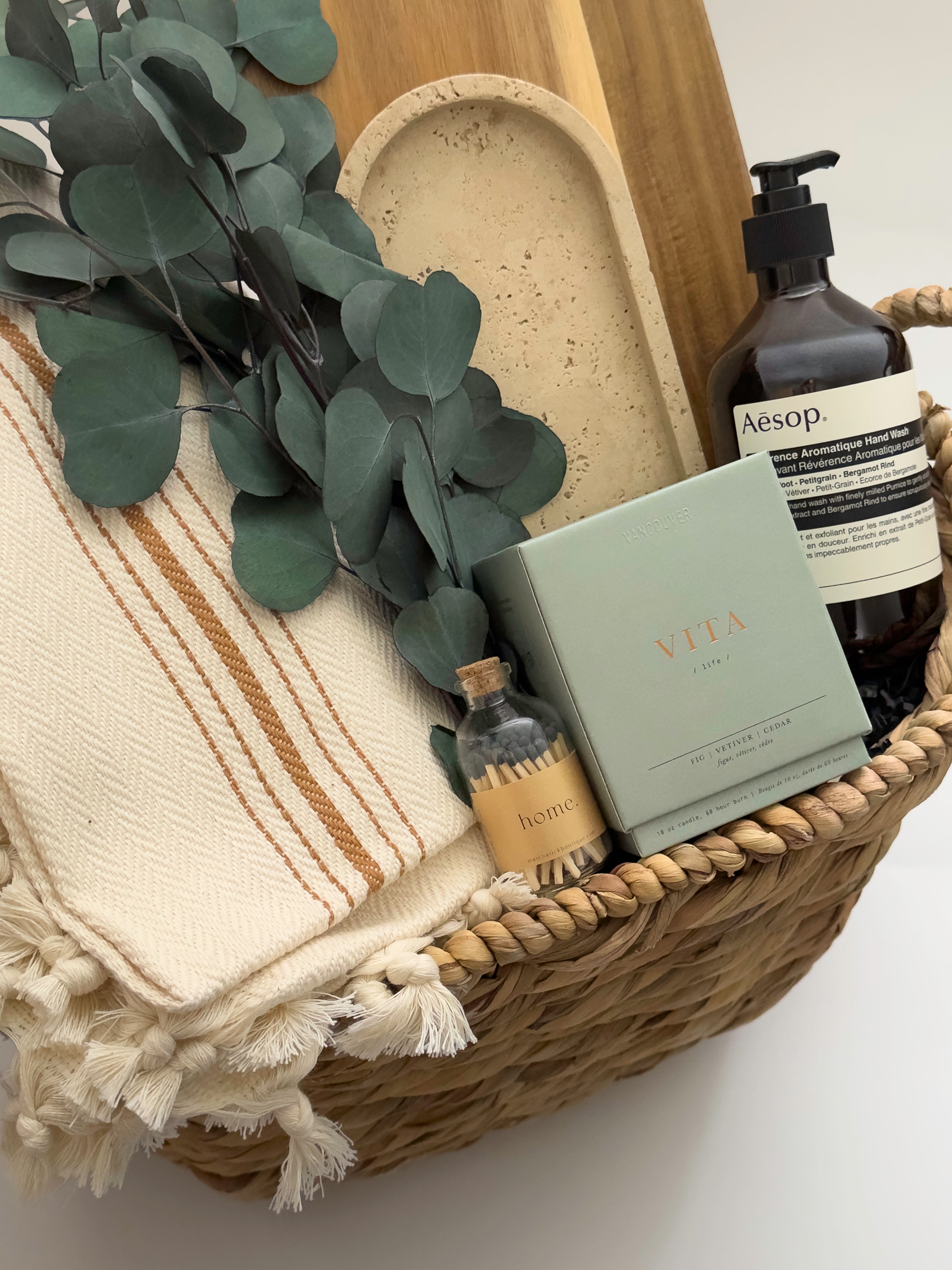 Demeure housewarming gift basket featuring Vancouver Candle Co candle Lynn and Liana wood board and preserved eucalyptus