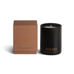Vancouver Candle Co. Hiems candle in geranium, patchouli, and cypress, shown beside its packaging, a premium candle featured in Muse Baskets and Co. corporate gift baskets