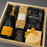 Gift basket with champagne, pretzels, popcorn, and on a grey background