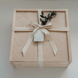 The West Village gift box from Muse Baskets and Co. shown closed, a Signature Luxe wood box tied with a cream cotton twill ribbon and dried eucalyptus, finished with a Muse Baskets and Co. gift tag reading Curated Artisan Gifting. A polished realtor closing gift, possession day gift, and corporate gift available for Vancouver, Lower Mainland, and Canada-wide delivery.