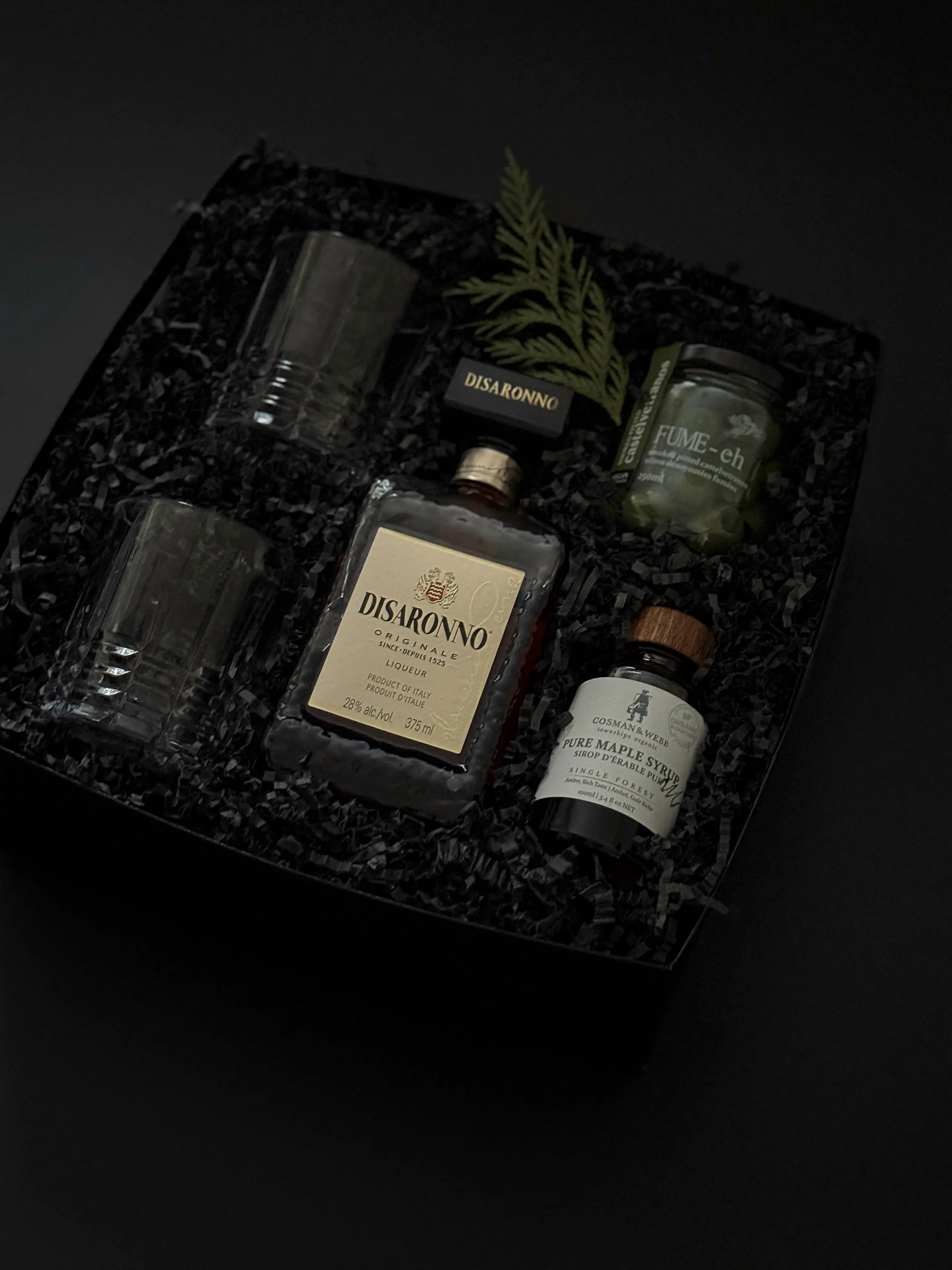 Gift box with crystal whiskey glasses, Amaretto, maple syrup, and Castelvetrano olives.